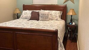 Ein Schlafzimmer mit einem hölzernen Bett, zwei Nachttischlampen, einem Deckenventilator, einer Sternen-Dekoration und einem Fenster mit Jalousien.