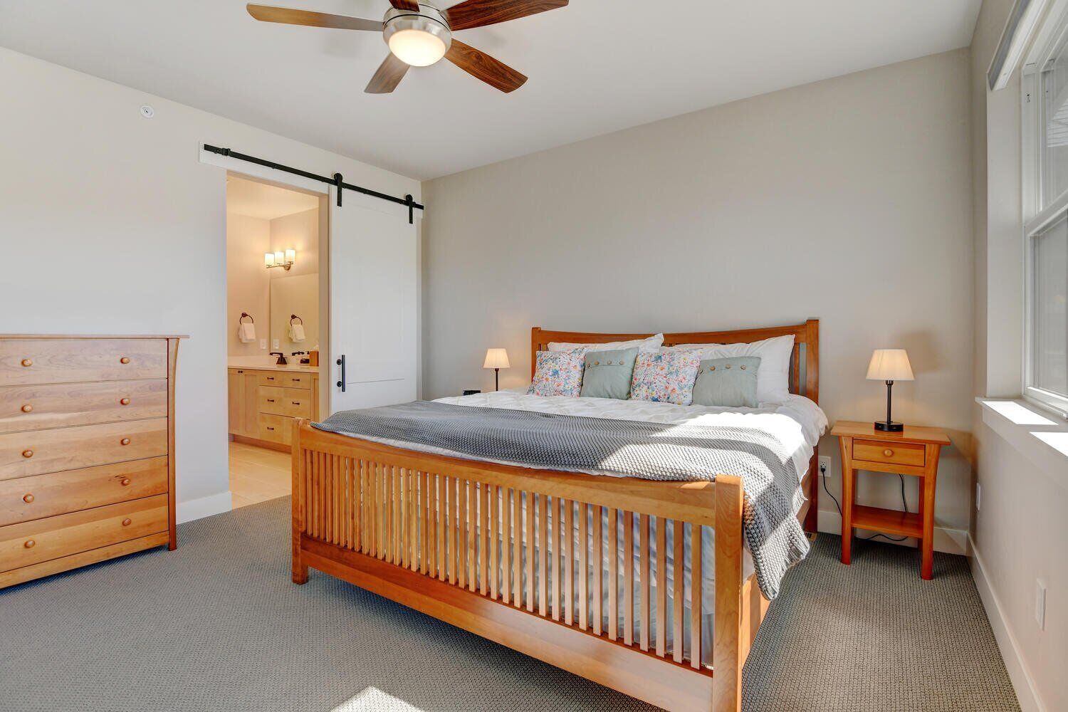 Une chambre à coucher avec un lit en bois, une table de chevet, une commode et un ventilateur de plafond.