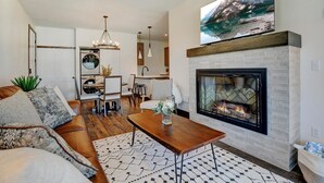 Una sala de estar moderna con chimenea, comedor y cocina.