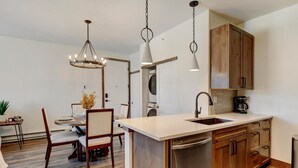 Una cocina moderna con armarios de madera, lavavajillas de acero inoxidable e iluminación colgante.