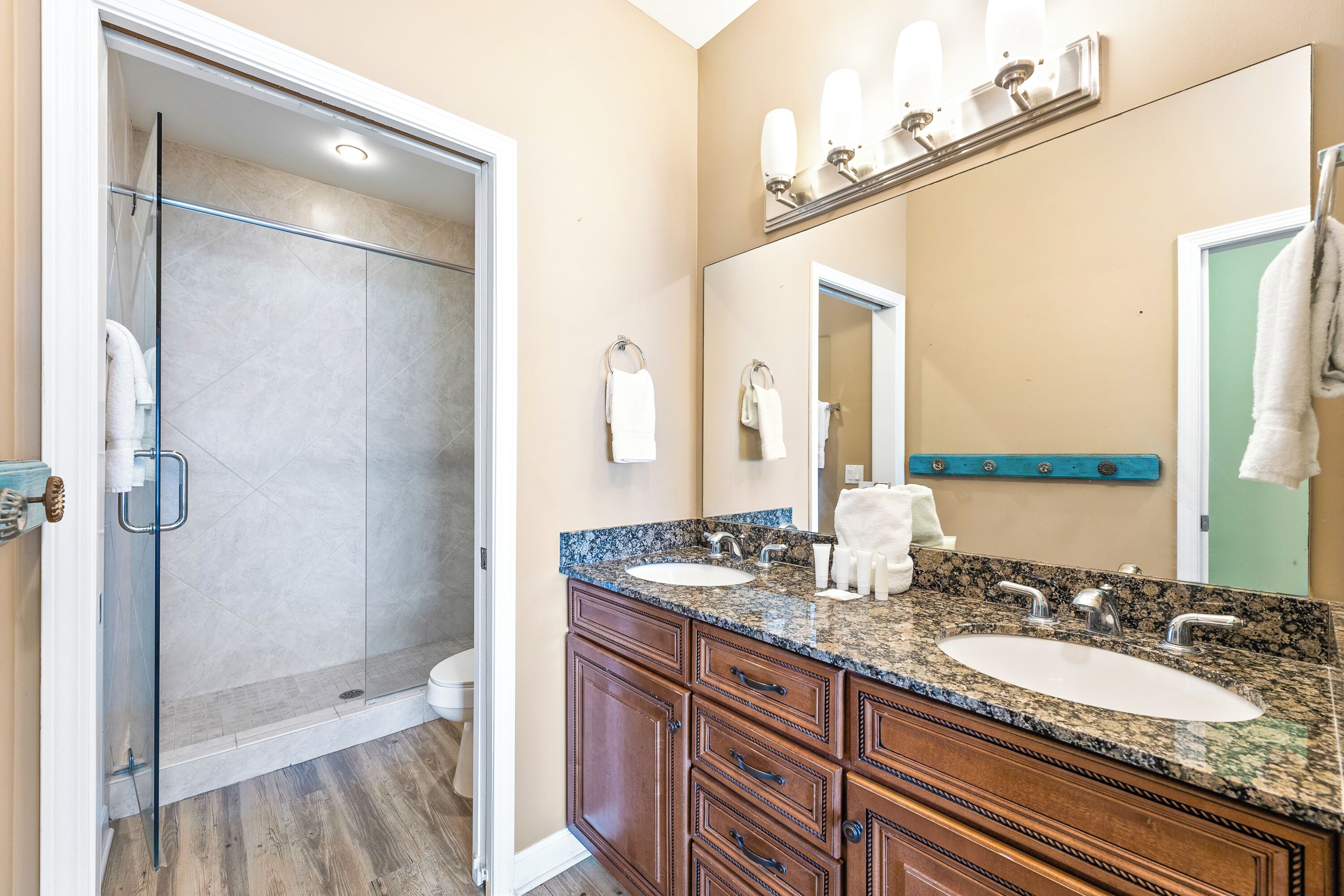Une salle de bain avec deux lavabos, une douche en verre, des meubles en bois et un grand miroir.