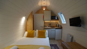 A compact room with a bed, a small kitchenette, a TV, and a window. - Cosy Couples Cabin in the Scottish Highlands (Tomintoul)