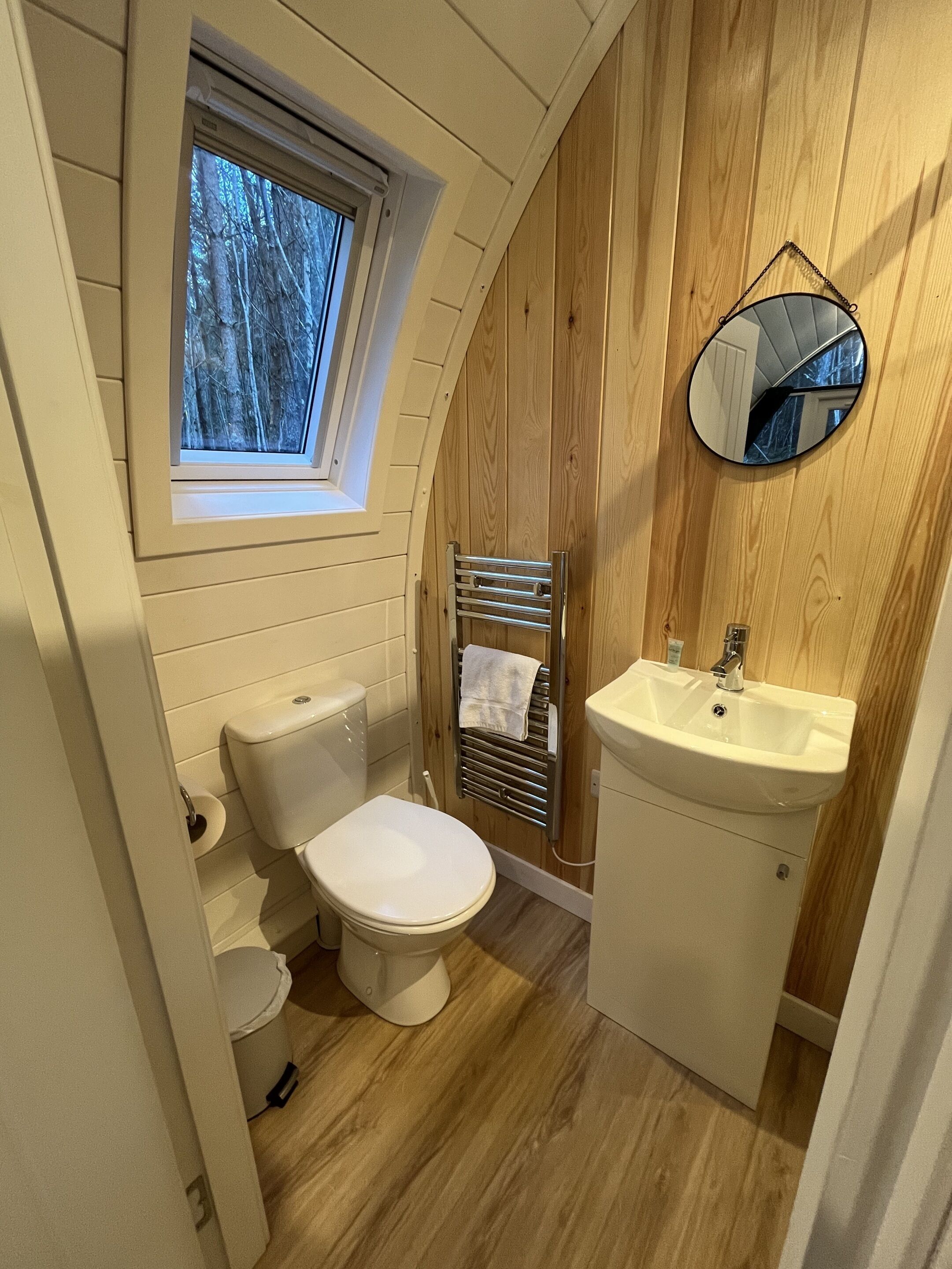 A compact bathroom with a toilet, sink, and a small window.