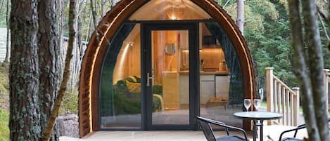 Ein gemütliches Holzhaus mit Glastür, einer kleinen Terrasse und zwei Stühlen sowie einer Deckfläche.