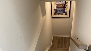 A wooden staircase with a framed informational poster above it. - Bright Private 2BR Suite | Near Niagara Falls | Family-Friendly (Pelham)