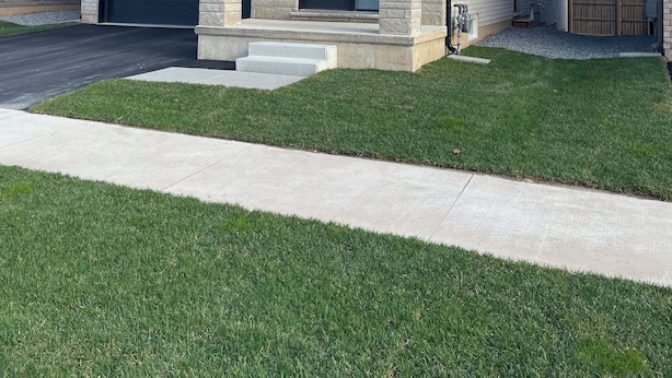 A modern two-story house with a garage, a well-maintained lawn, and a clear sky. - Bright Private 2BR Suite | Near Niagara Falls | Family-Friendly (Pelham)