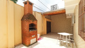 Een terras met een bakoven, een tafel en vier stoelen.