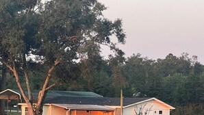 Una casa con porche, una pequeña terraza y un patio cercado.