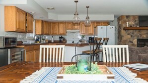 Una cocina moderna con armarios de madera, una encimera blanca y una zona de comedor con mesa y sillas de madera.