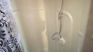 A shower with a handheld showerhead and a wall-mounted faucet. - Lakeside 2-bedroom RV in charming Hartsville with AC, WiFi (Hartsville)