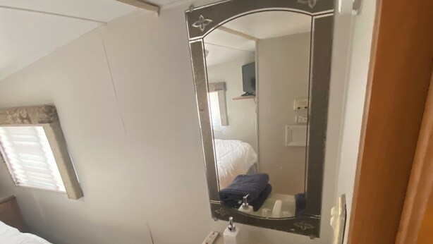 A compact bathroom with a mirror, sink, and two towels. - Lakeside 2-bedroom RV in charming Hartsville with AC, WiFi (Hartsville)