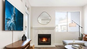 A living room with a fireplace, a sofa, a coffee table, and a TV.