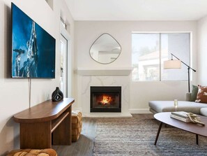 A living room with a fireplace, a sofa, a coffee table, and a TV.