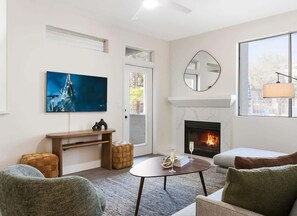 Ein Wohnzimmer mit Kamin, Fernseher und einer Couch.