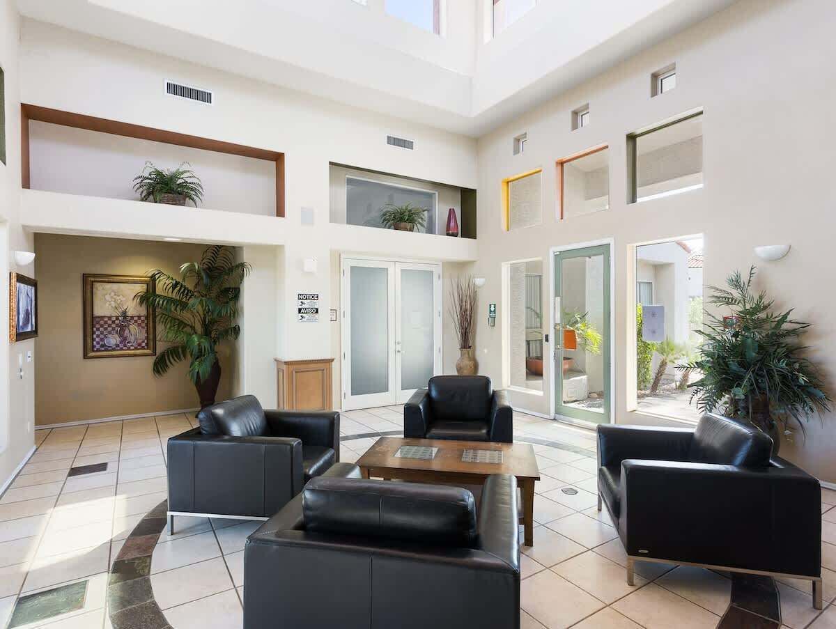 A spacious lobby with a high ceiling, multiple seating areas, and large windows allowing natural light.
