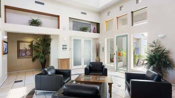 A spacious lobby with a high ceiling, multiple seating areas, and large windows allowing natural light.