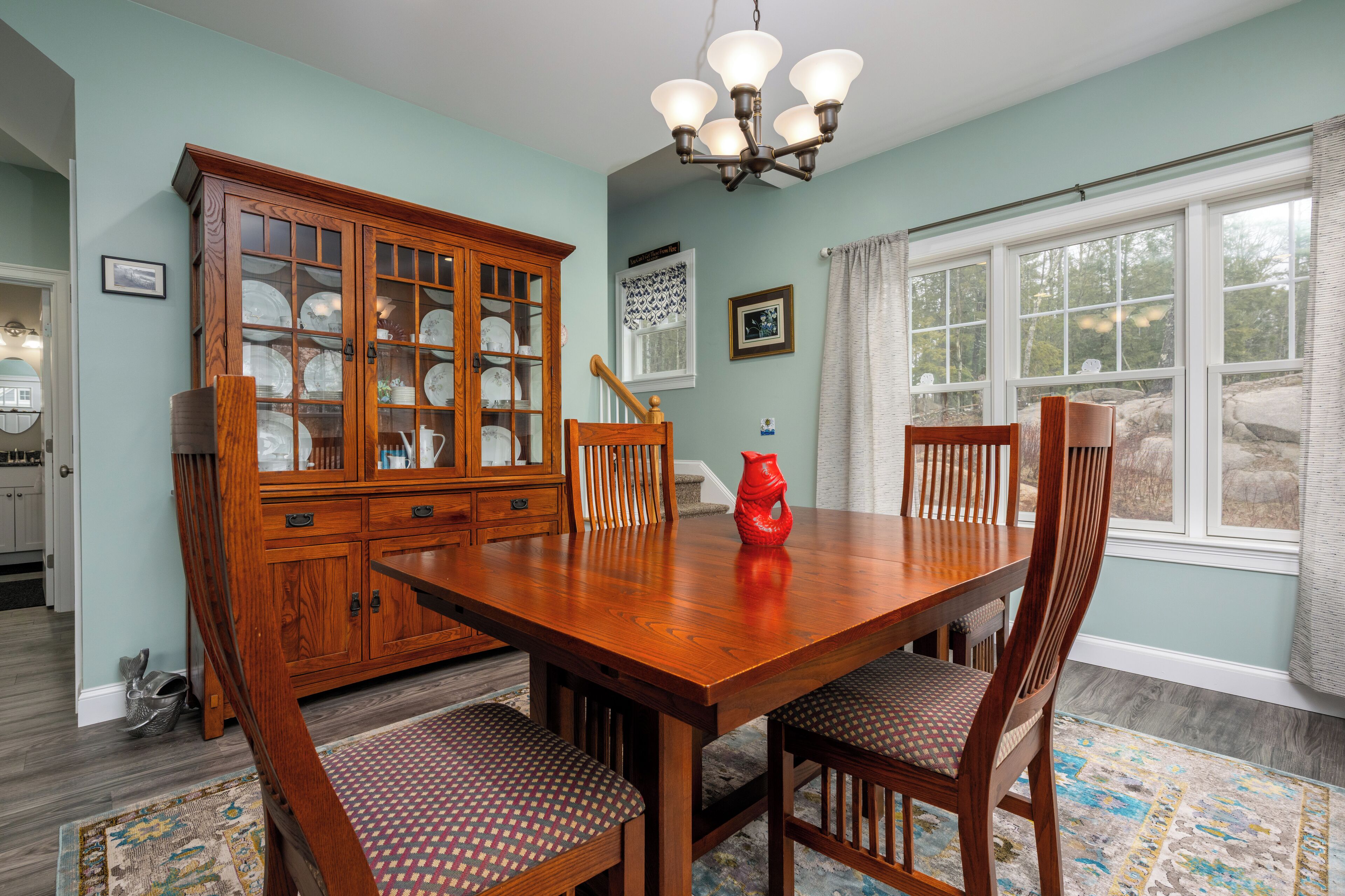 A dining room with a wooden table, chairs, and a cabinet.
