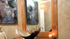 Une salle de bain avec un meuble-lavabo en bois, un lavabo doté d’un receveur original et un grand miroir.