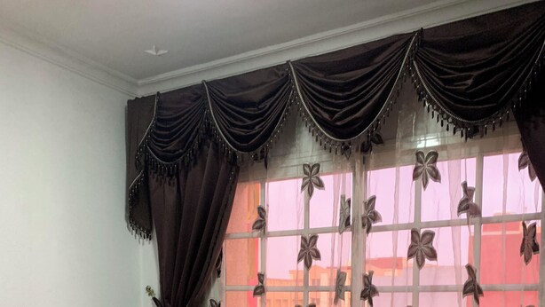 Een slaapkamer met een houten bed, een nachtkastje, een stoel en een raam met gordijnen.