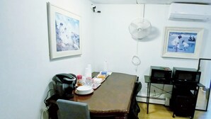 Una sala de conferencias con una mesa de madera, sillas, una pizarra y dos cuadros en la pared.