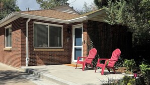 A small brick house with a front porch, two red Adirondack chairs, and a small garden area. - Crown Hill Retreat - Hot Tub/Yard/Parking (Lakewood)