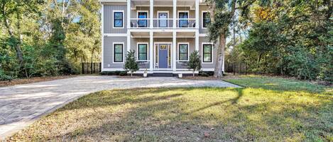A two-story house with a front porch, a driveway, and a well-maintained lawn.