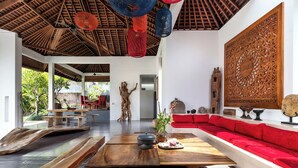 Un vaste espace de vie doté d’un plafond en bois, d’un long canapé rouge et d’une table à manger avec des bancs.