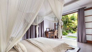 Une chambre à coucher avec un lit à baldaquin, un bureau et une vue sur le jardin.