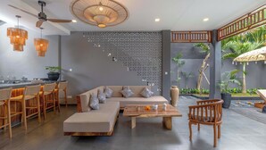 Un espace de vie moderne comprenant un canapé, des chaises en bois, une table basse et un panneau décoratif mural.