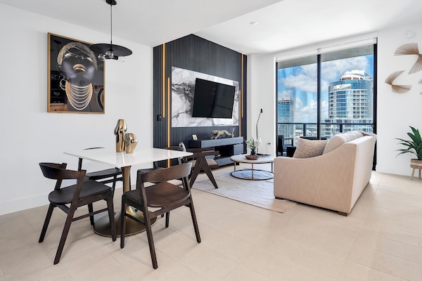Living room with dining table for 4, queen-size sofa bed, and smart TV.