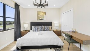 Une chambre d’hôtel moderne, dotée d’un grand lit, d’un bureau et offrant une vue sur l’extérieur.
