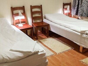 A room with two single beds, a small wooden table with a lamp, and a chair. - 6 Person Holiday Home in Hamnvik (Ibestad)