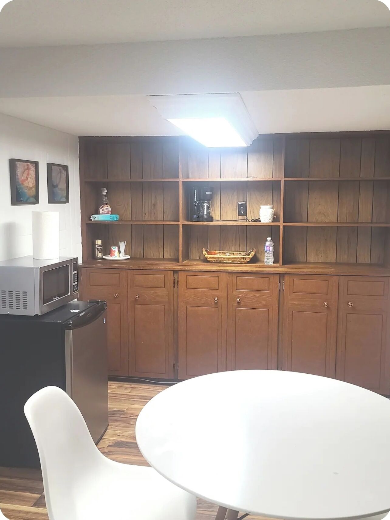 A compact kitchen with wooden cabinets, a microwave, and a dining table with chairs.