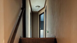 Eine Holztreppe mit Geländer auf der linken Seite, die zu einer Tür oben führt.