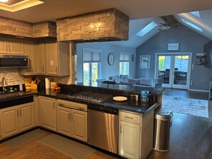 Een moderne keuken met een achterwand van steen, roestvrijstalen apparatuur en een groot eiland.