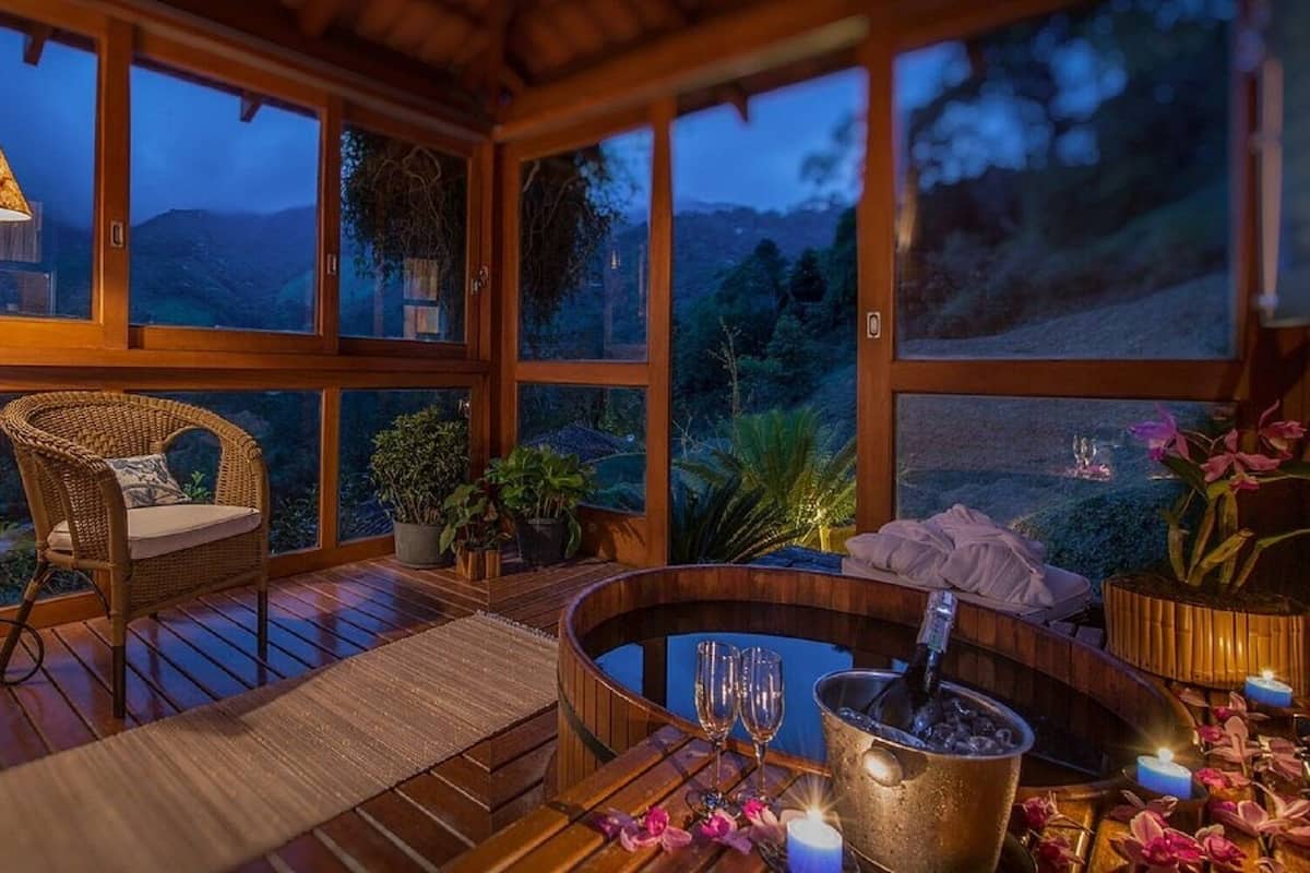 A cozy room with a wicker chair, a small table with a candle, and a hot tub.