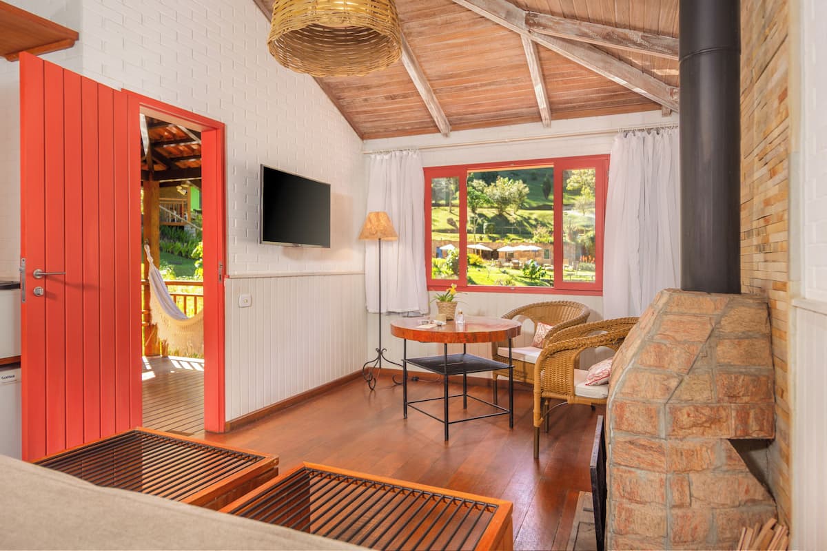 A cozy room with a stone fireplace, a television mounted on the wall, and a wicker chair.
