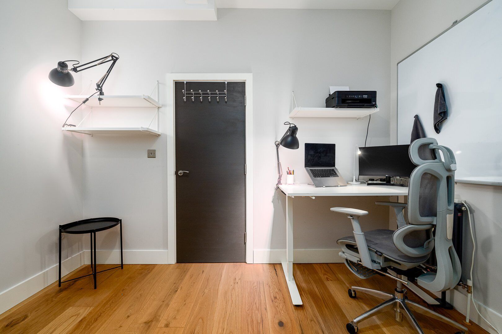 Un espace de bureau compact comprenant un bureau, une chaise, un ordinateur et des étagères.