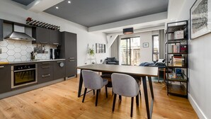Cocina moderna con comedor, que cuenta con un salpicadero de azulejos hexagonales, electrodomésticos de acero inoxidable y una mesa de comedor de madera con dos sillas.