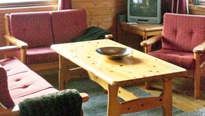 A small room with two red chairs, a wooden table with a bowl, and a television on a wooden stand. - 8 Person Holiday Home in Nordfjordeid-by Traum (Stad)