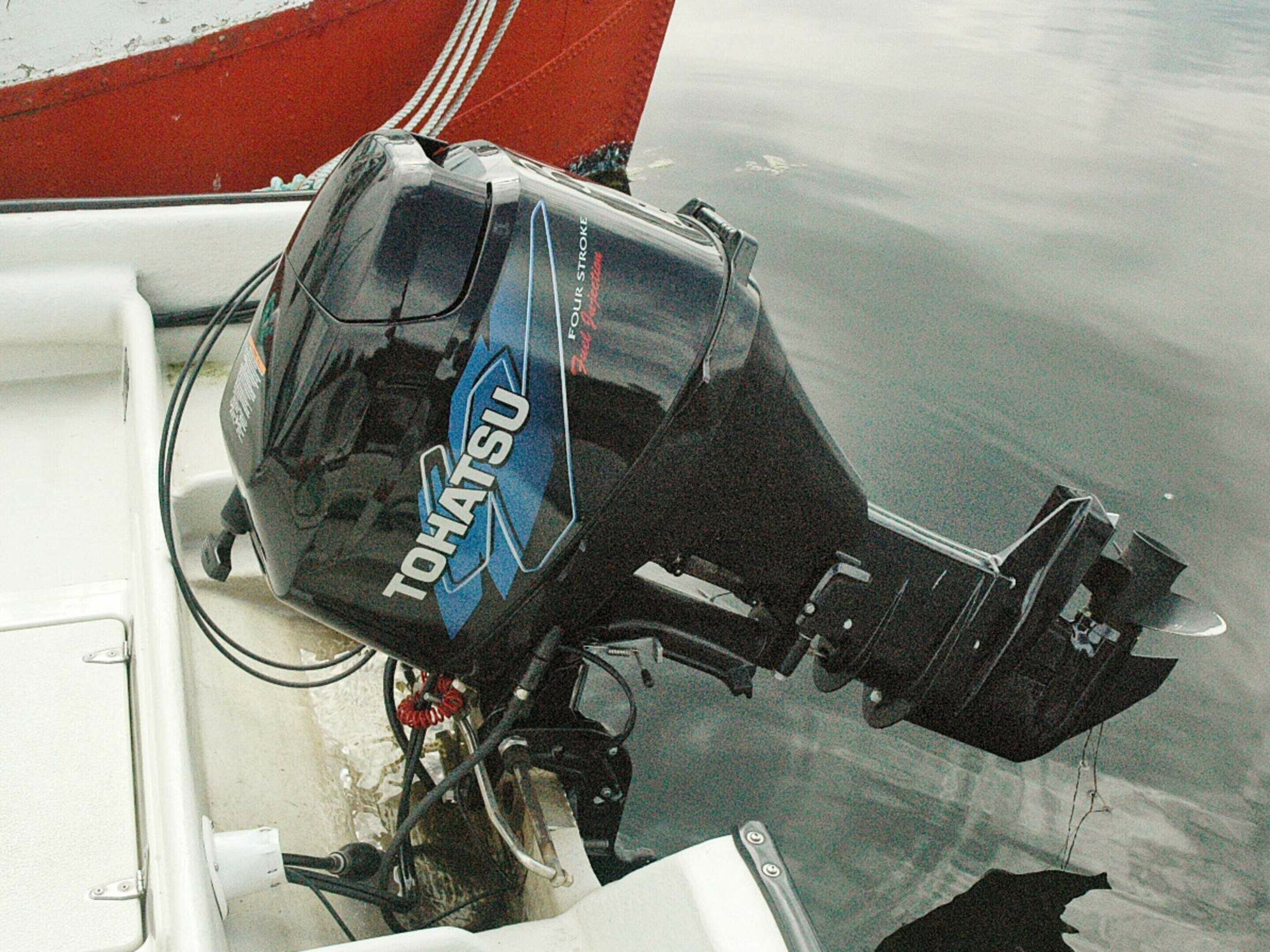 A boat with a black outboard motor labeled "TOHATSU" and a red section on the side.