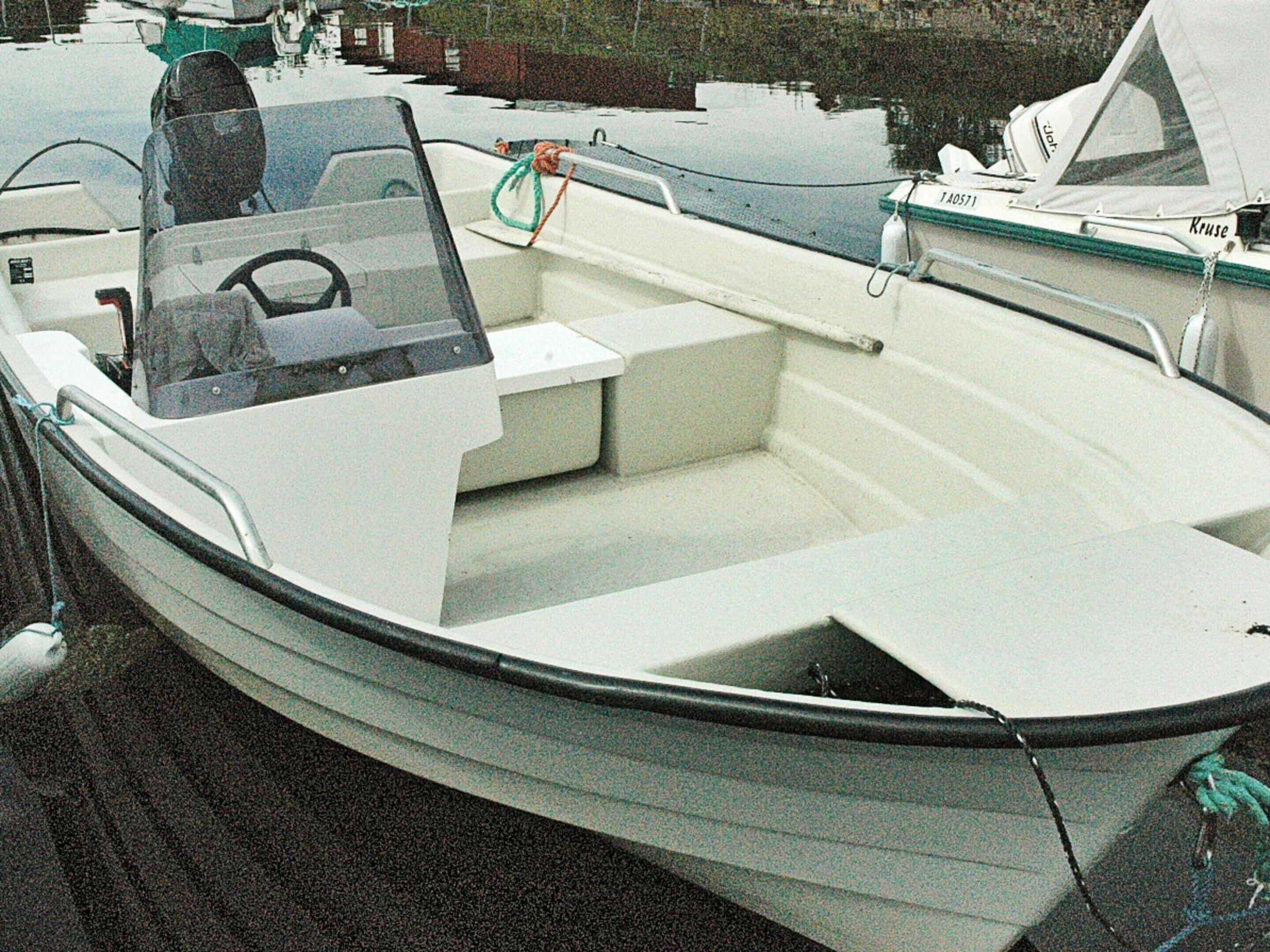 A small, white motorboat docked at a marina.