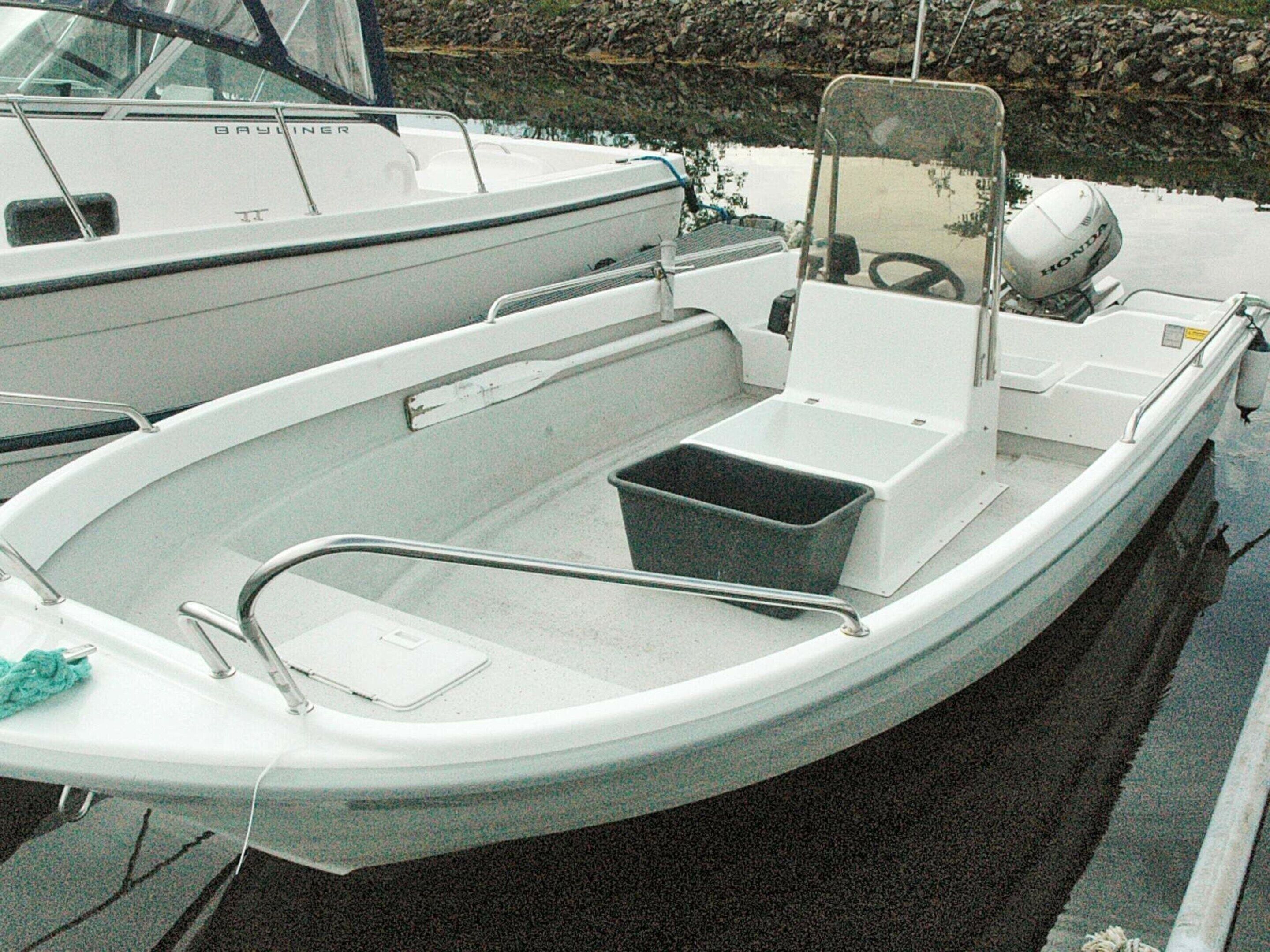 A small, white motorboat with a cabin, a steering wheel, and a Honda outboard motor.