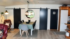 A dining area with a table set for four, a black sliding door, a white refrigerator, and a wooden cabinet. - 4 Star Holiday Home in Aram (Vanylven)