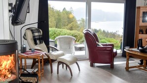A cozy living room with a fireplace, comfortable seating, and a view of a lake. - 4 Star Holiday Home in Aram (Vanylven)