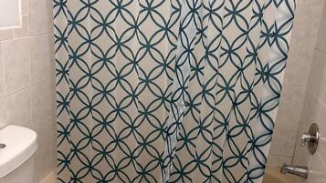 A bathroom with a toilet, a bathtub, and a shower curtain with a geometric pattern.