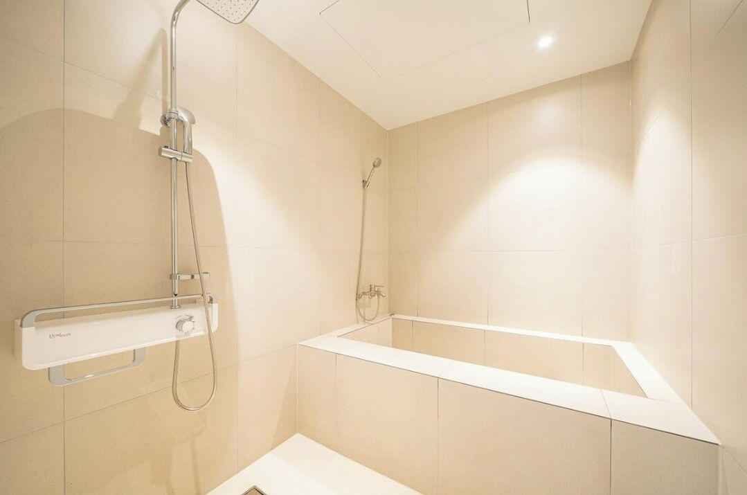 Un baño moderno con bañera, ducha y barra de apoyo.