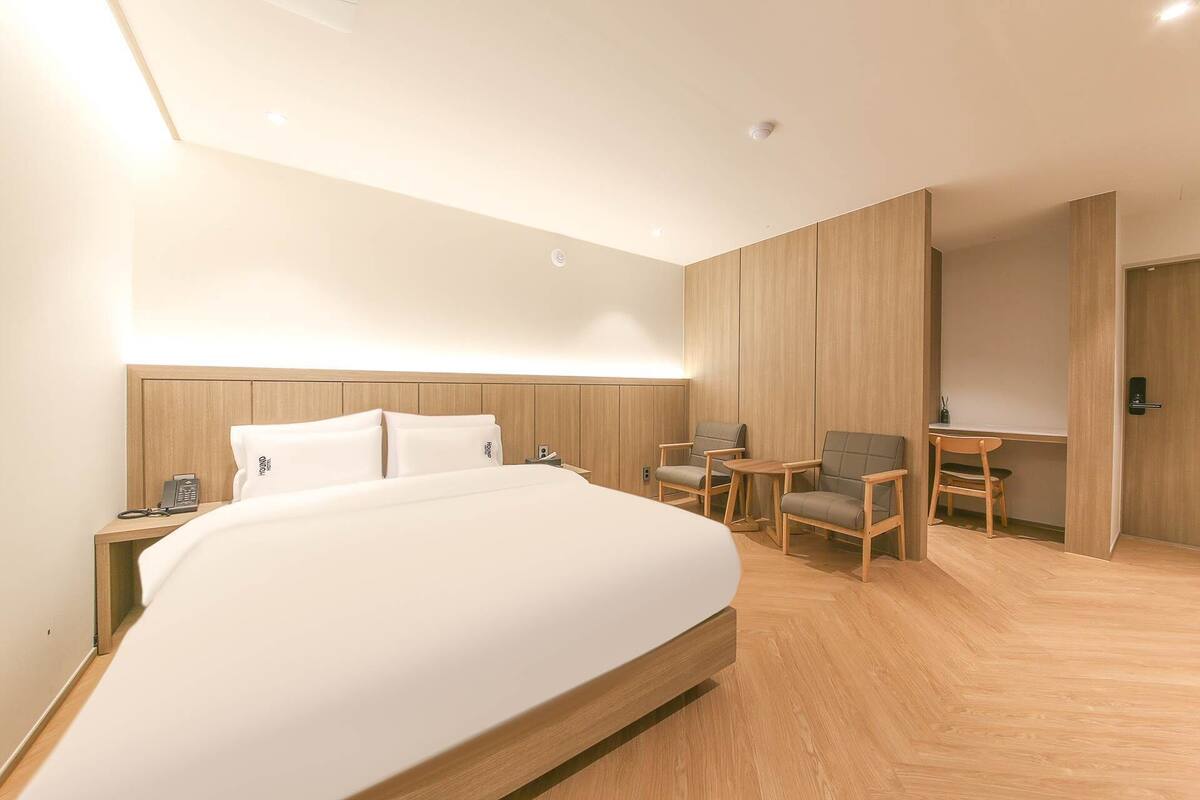 Una habitación de hotel moderna con una cama grande, un escritorio, dos sillas y una pequeña mesa.