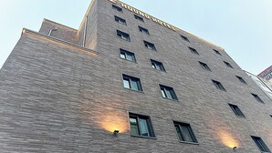 A multi-story building with a brick facade, multiple windows, and a sign indicating it is a hotel. - Hound Hotel Jeonju Deokjin (Jeonju)