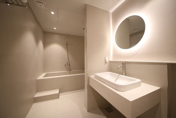 A modern bathroom with a bathtub, a sink, and a mirror.